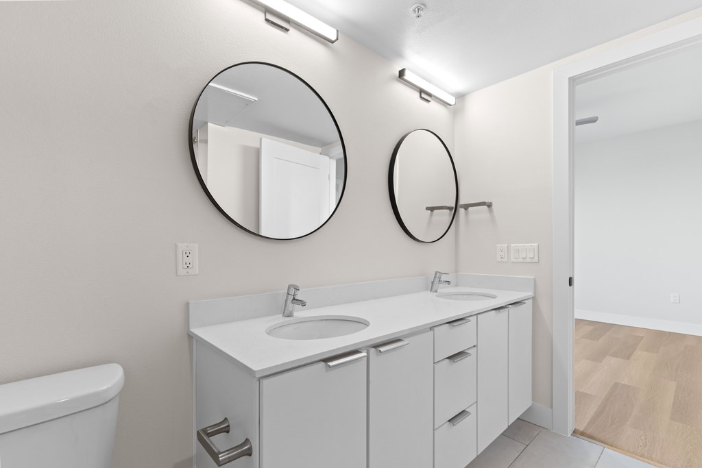 A white bathroom with a sink, mirror, and bathtub.