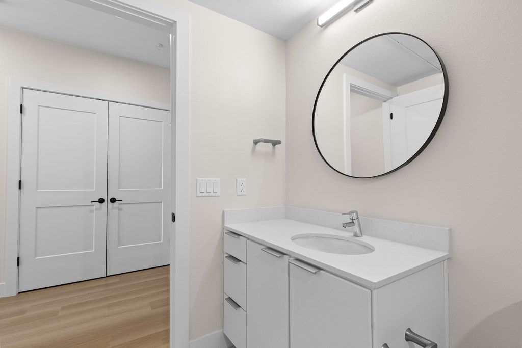 A bathroom with a white sink and a round mirror.