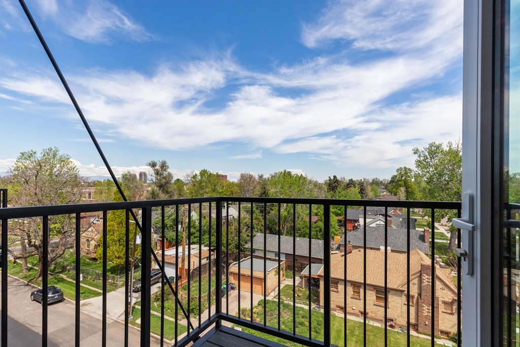 A balcony with a black railing overlooks a residential neighborhood.