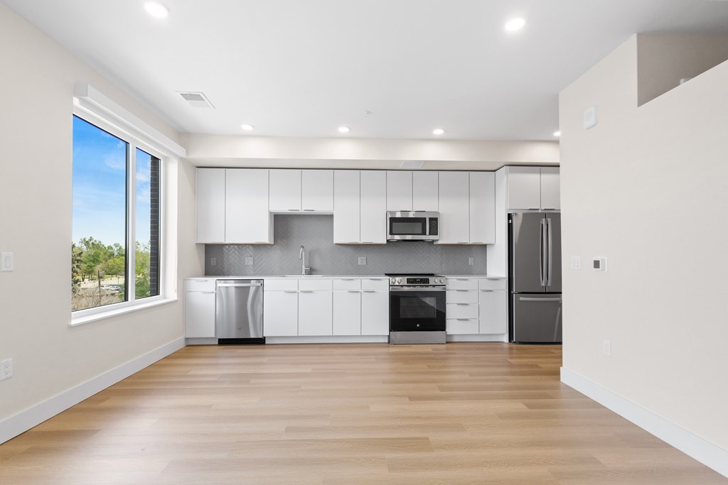 A modern kitchen with white cabinets and stainless steel appliances.