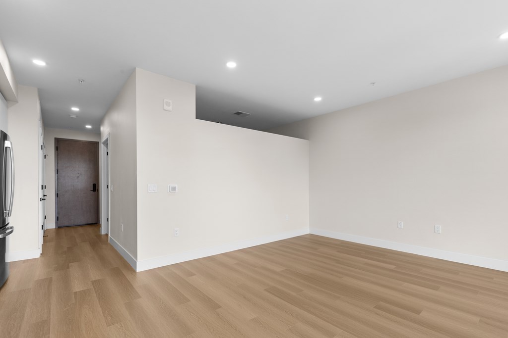 A large empty room with wooden flooring and white walls.