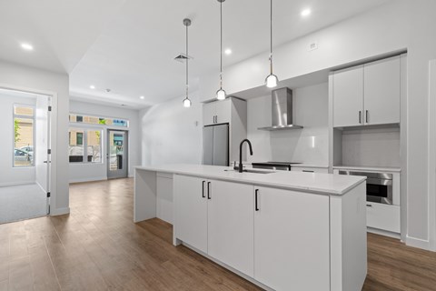 A modern kitchen with white cabinets and a wooden floor.