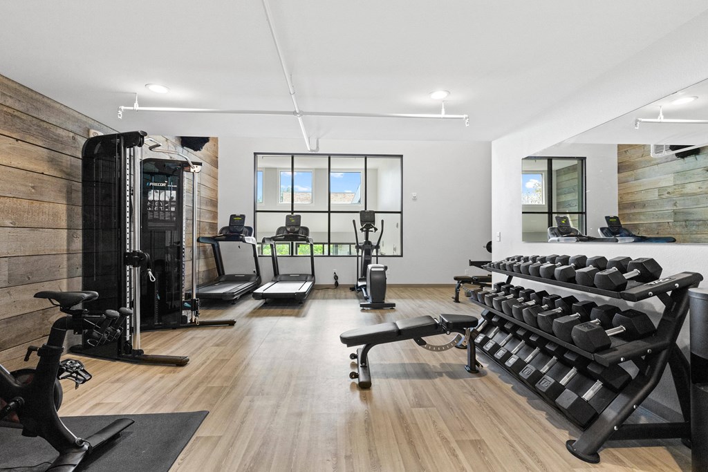 a gym with weights and exercise equipment on a wooden floor