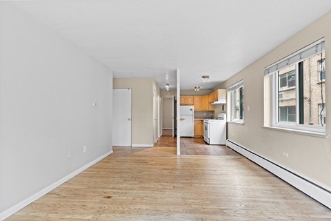 an empty apartment with a wood floor and a kitchen