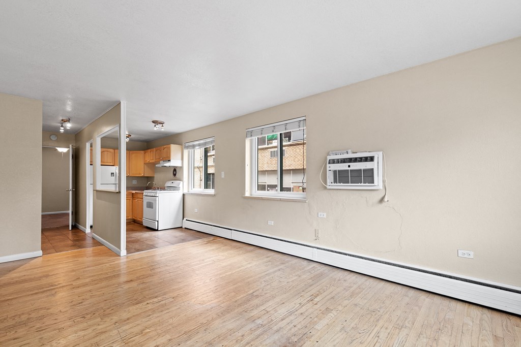 the living room and kitchen of an empty house with wood flooring