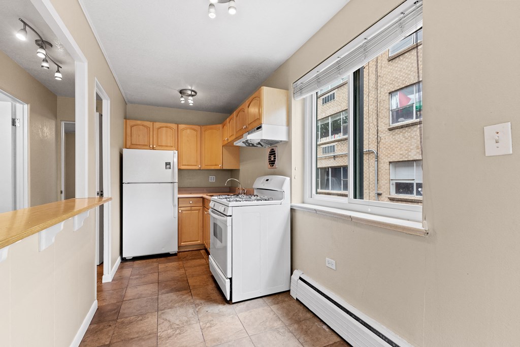 an empty kitchen with white appliances and a window