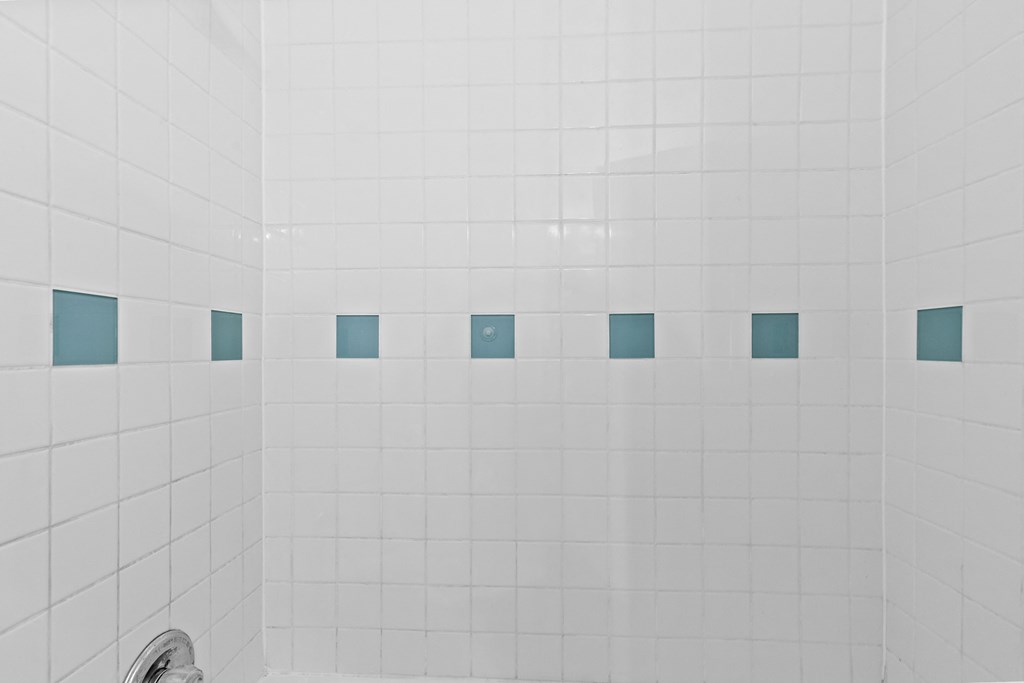 a white tiled bathroom with white and blue tiles