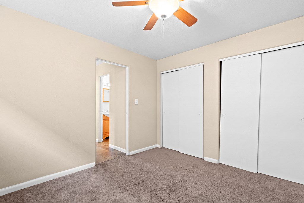 an empty room with white closets and a ceiling fan