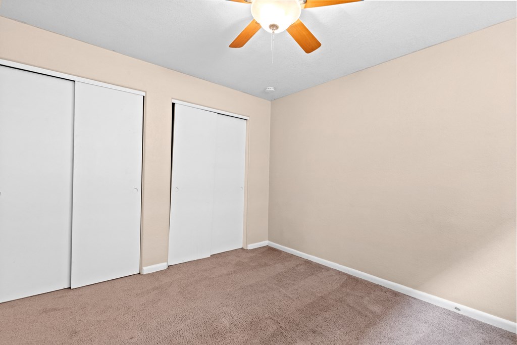 a bedroom with three closets and a ceiling fan