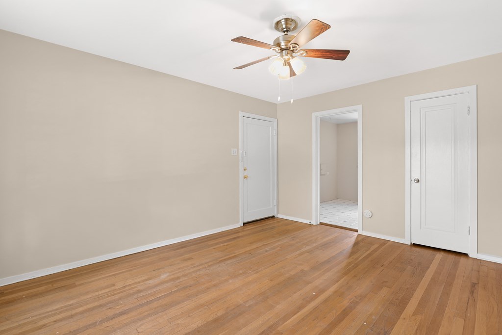 an empty living room with wood floors and a ceiling fan