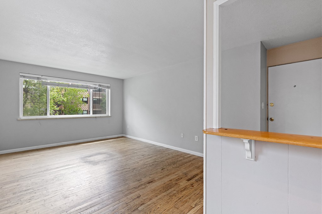 the living room and dining room of an empty house with wood floors and a window