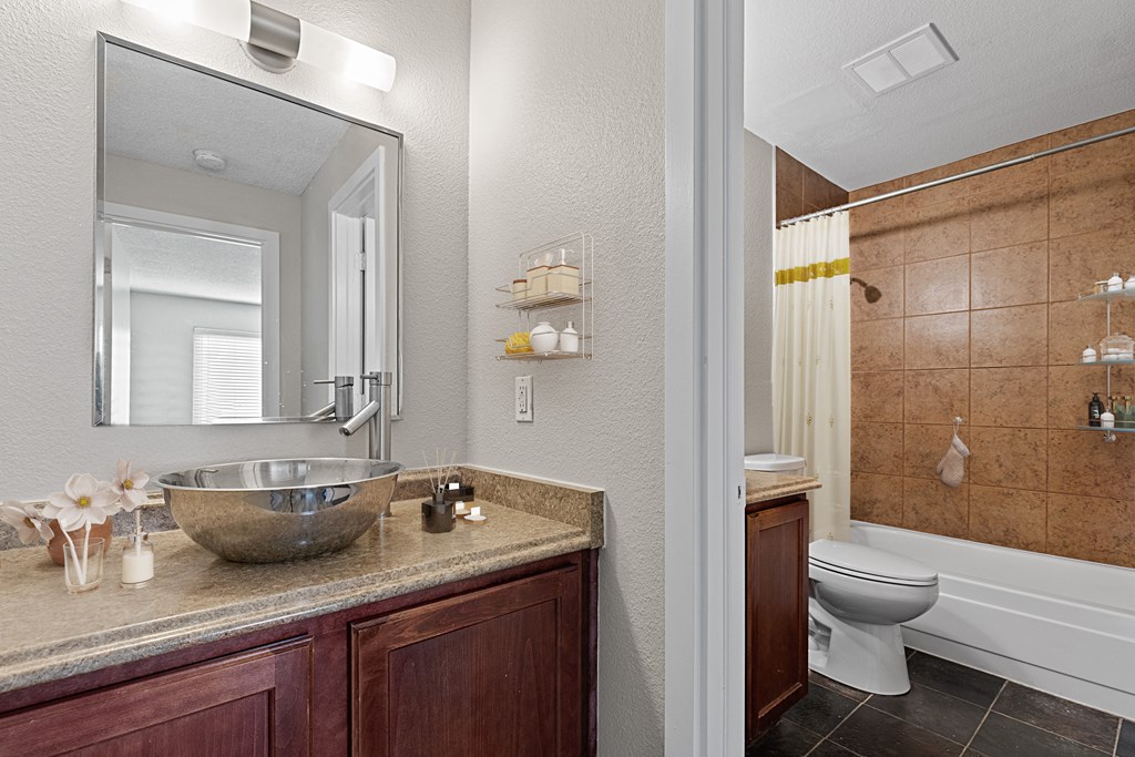 A bathroom with a brown counter top and a white toilet.