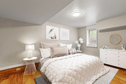 A bedroom with a large bed, a white bedside table, and a white dresser.