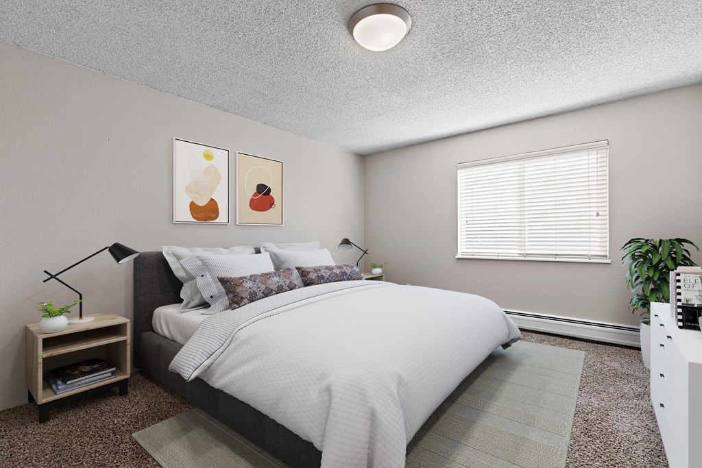 A bedroom with a large bed and a nightstand with a plant on it.