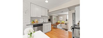 a kitchen and living room with white cabinets and a wood floor