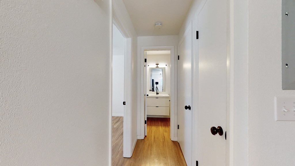 A hallway with a white door and a mirror on the wall.