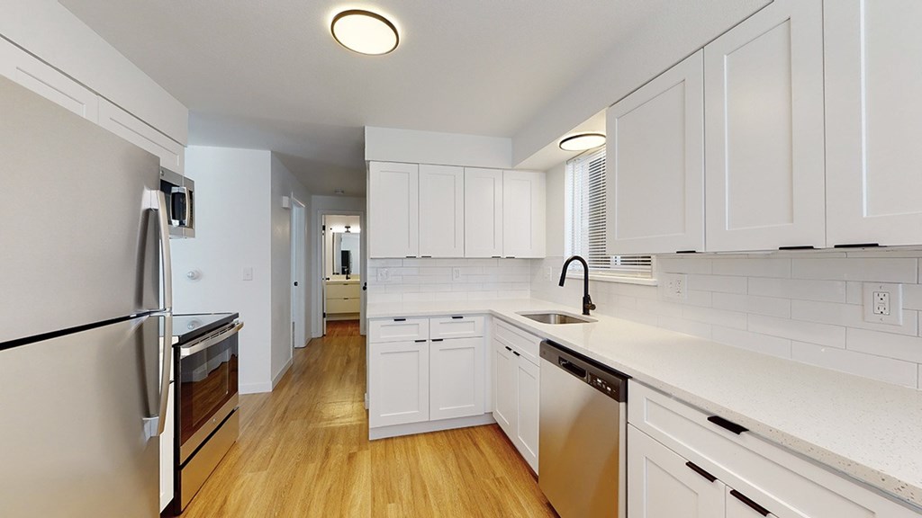 A kitchen with white cabinets and a stainless steel refrigerator.