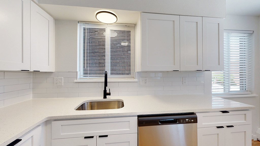 A kitchen with white cabinets and a stainless steel dishwasher.