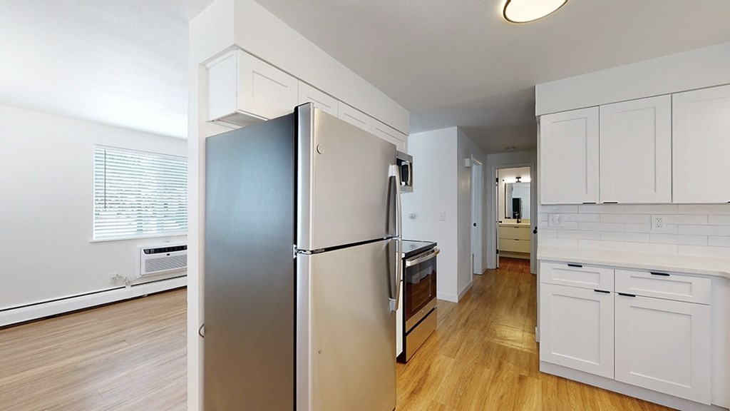 A kitchen with a refrigerator and wooden floors.