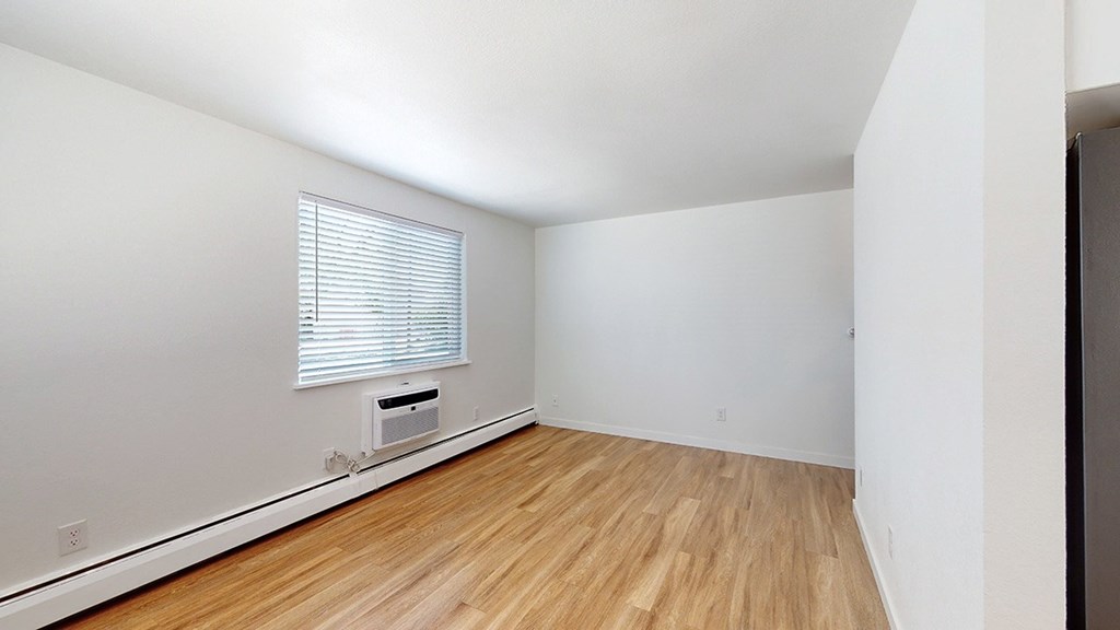 A room with wooden flooring and a window with blinds.