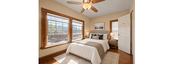 A bedroom with a large bed and a ceiling fan.