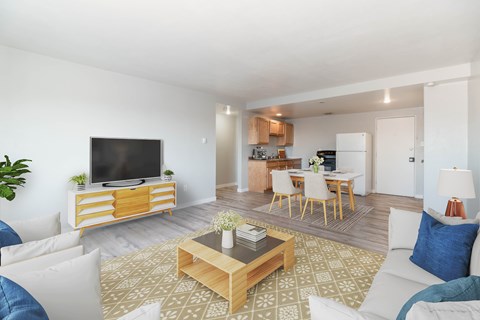 A living room with a white couch, a wooden coffee table, and a television on a wooden stand.