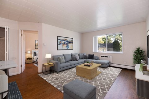 A living room with a grey couch, a coffee table, and a painting on the wall.