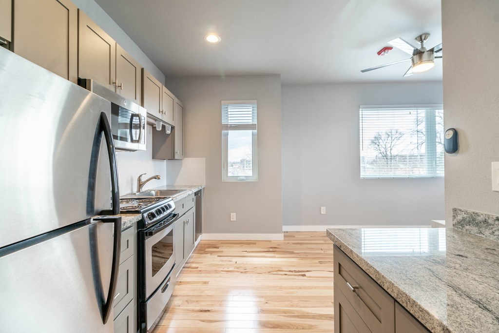 A modern kitchen with a stainless steel refrigerator and wooden flooring.