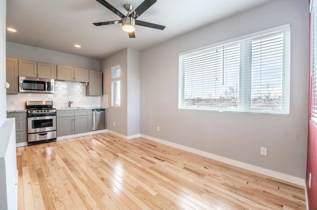 A kitchen with wooden floors and a ceiling fan.
