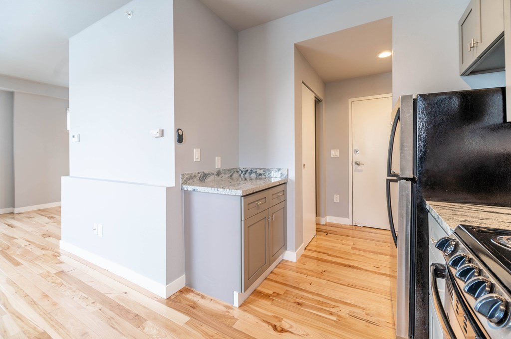A kitchen with a black refrigerator and wooden floors.