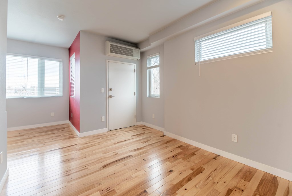 A room with wooden flooring and a window with blinds.
