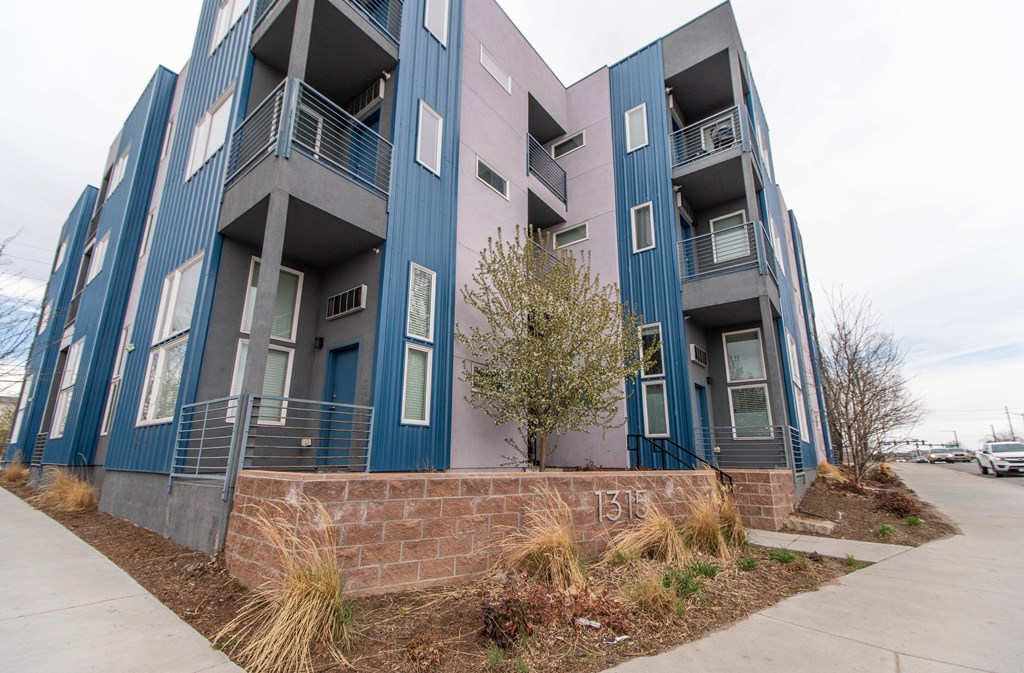 A modern apartment building with blue and pink balconies.