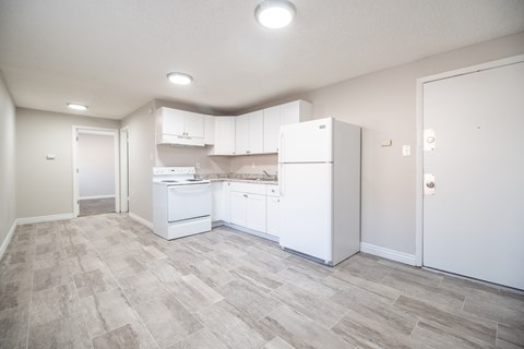 A kitchen with white appliances and cabinets in a room with a tiled floor.