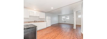 A kitchen with a black stove top oven and wooden floors.