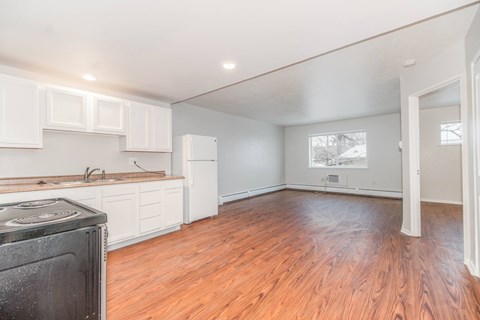 A kitchen with a black stove top oven and wooden floors.