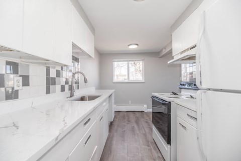 A modern kitchen with white cabinets and a marble countertop.
