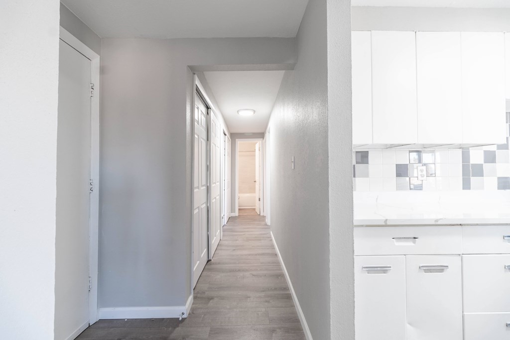 A long hallway with white walls and a tiled floor.