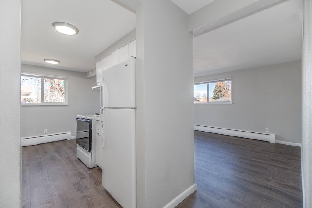 A kitchen with a white fridge and wooden floors.