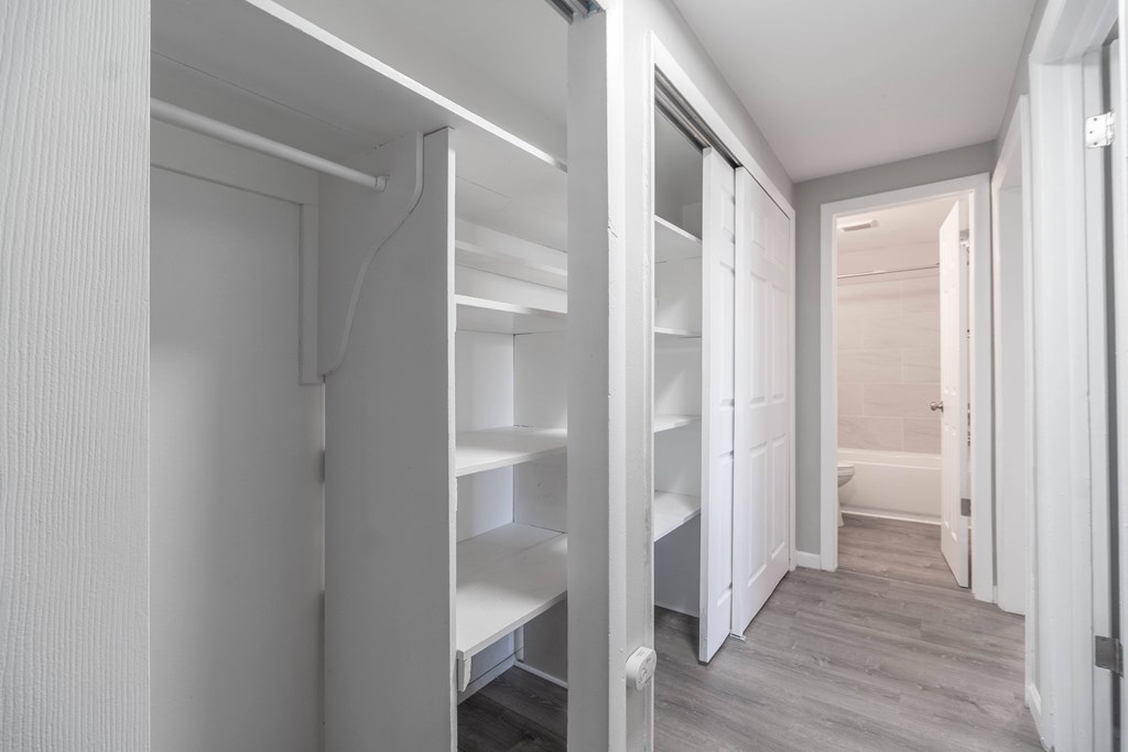 A white hallway with a bench and a door.