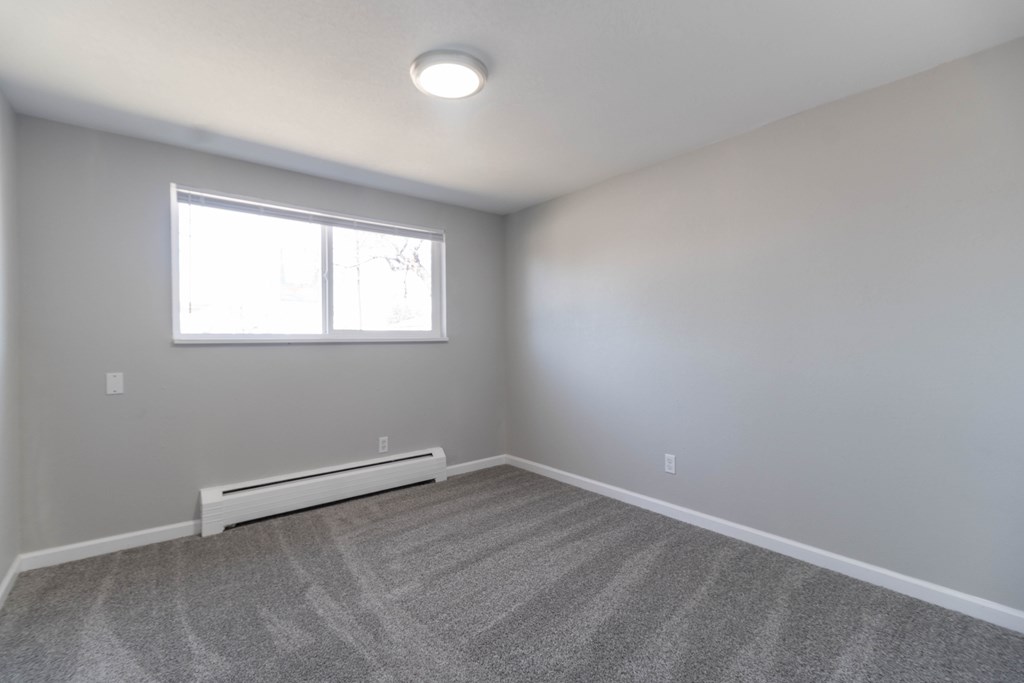 A room with a carpeted floor and a window.