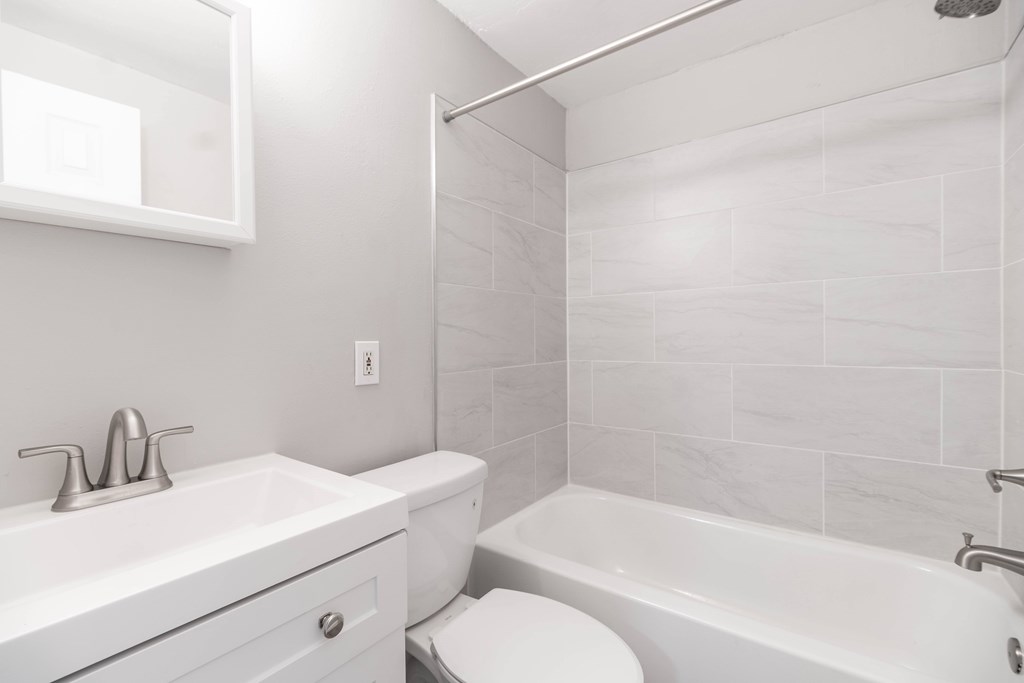 A white bathroom with a toilet, sink, and bathtub.
