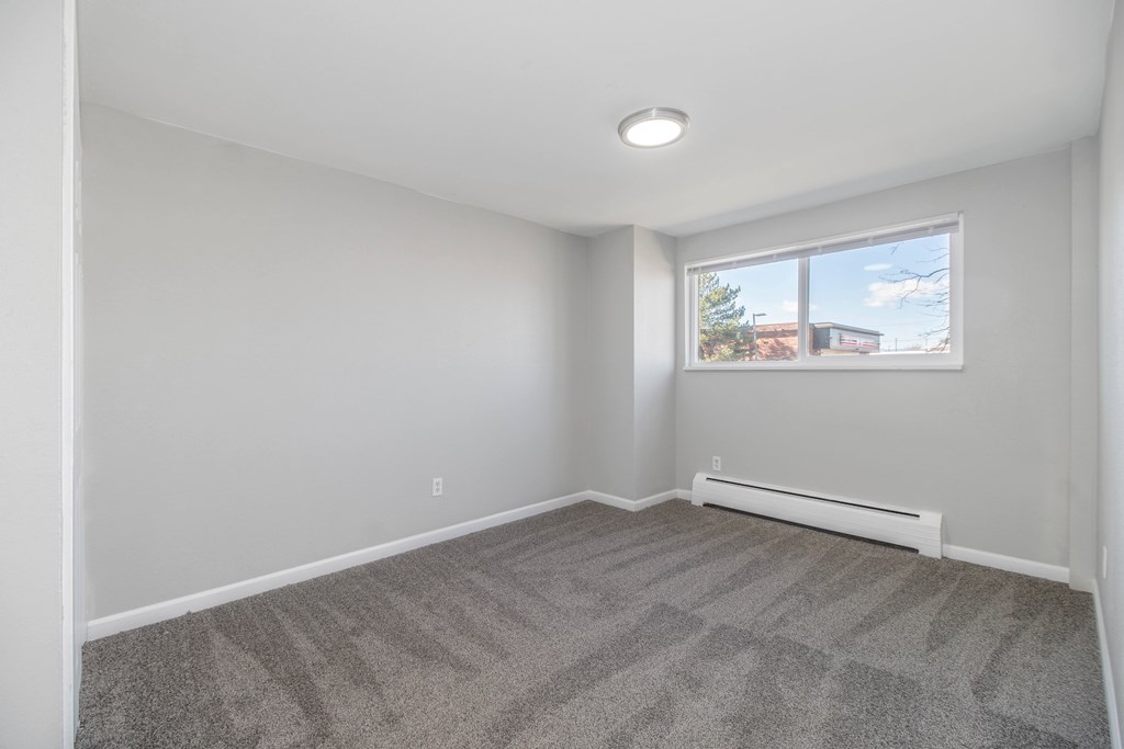 A room with a carpeted floor and a window.