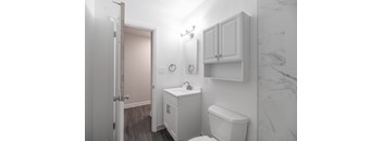 A white bathroom with a toilet, sink, and cabinets.