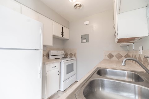 A small kitchen with a white fridge, microwave, and stove.