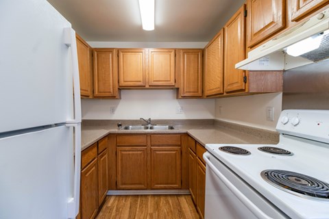 A kitchen with wooden cabinets and a white stove.