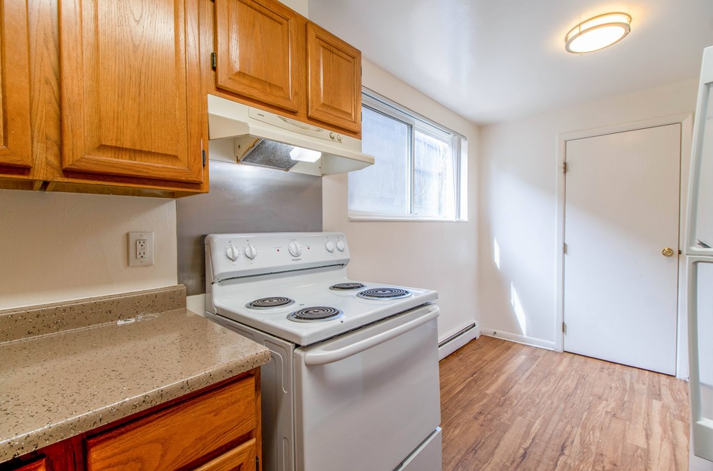 A kitchen with a stove and wooden cabinets.