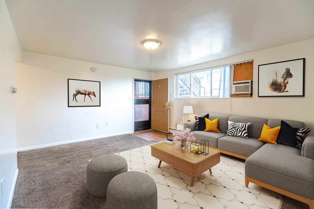 A living room with a grey couch, a coffee table, and a painting of a moose on the wall.