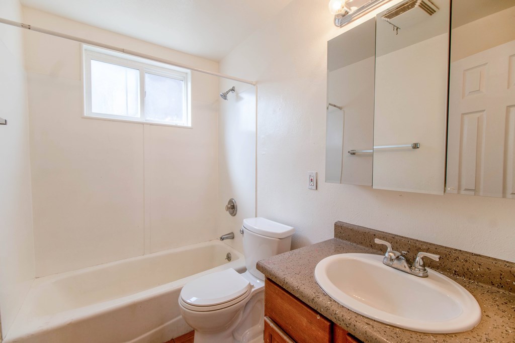 A white toilet sits next to a bathtub in a bathroom.