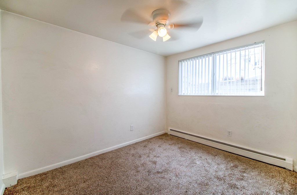 A room with a ceiling fan and a window with blinds.