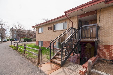 A brick building with a black railing staircase.